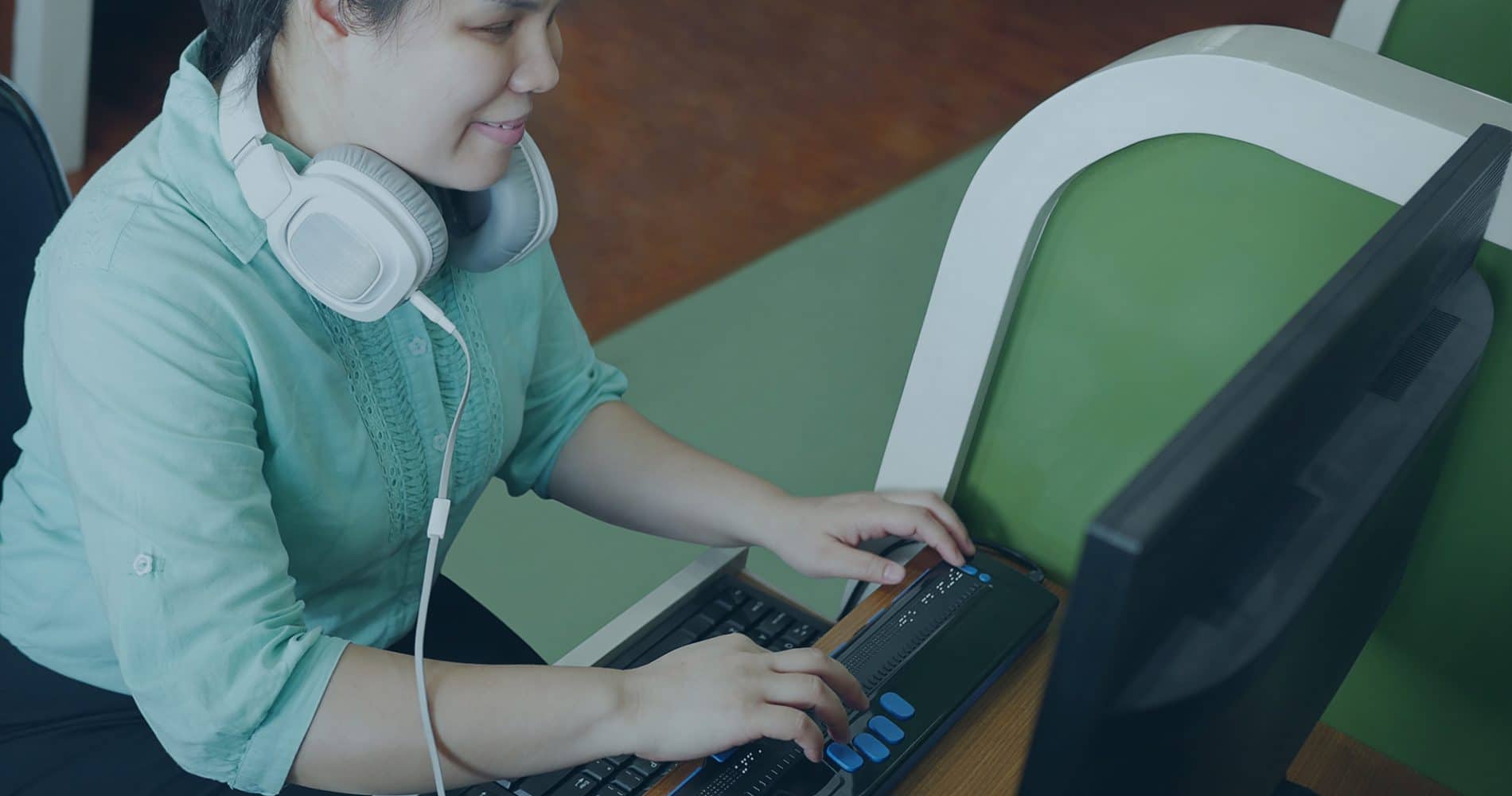 Henkilö istuu tietokoneen ääressä ja kuulokkeet ovat hänellä niskan takana. Tällä kuvaraan Flairen saavutettavuusselostetta
